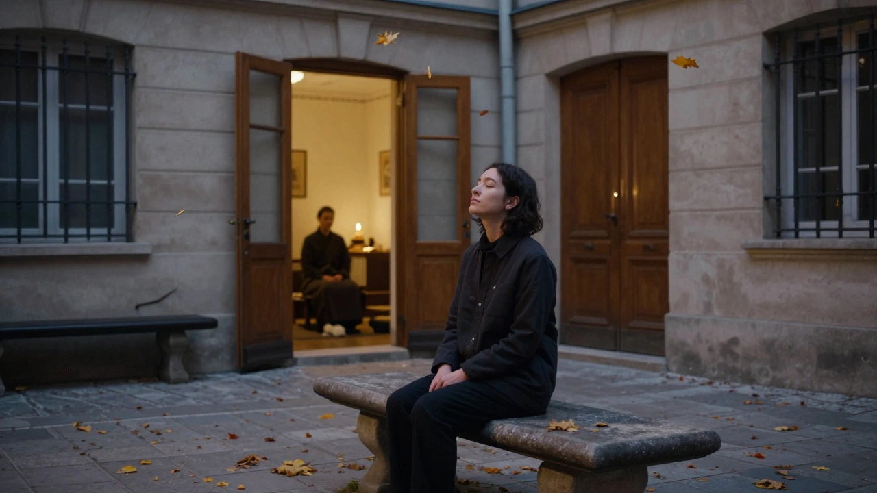 Personne assise sur un banc en automne, dans une cour parisienne, au crépuscule, entourée de feuilles tombées et d&#039;une porte entrebâillée.
